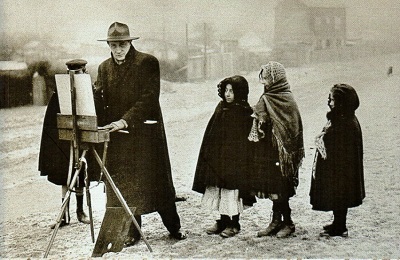 Francisque Poulbot peint, entouré d'enfants de la Butte Montmartre.